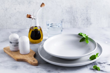 Empty set of plates for soup on a table with spices and olive oil in a decanter.