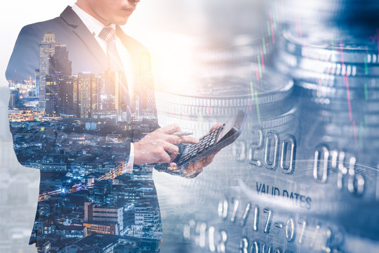 the double exposure image of businessman using a calculator overlay with cityscape and coin stack image and white copy space. the concept of accounting, business, financial, economy and investment.