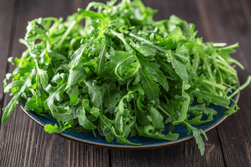 Fresh green arugula in bowl on table. Arugula rucola for salad. Close up of fresh green healthy food. Diet concept