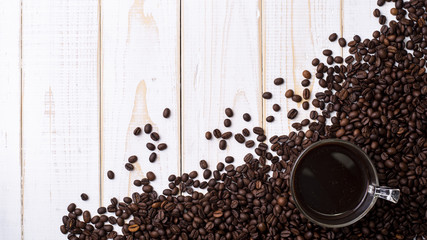 Coffee cup and coffee beans on white wooden table