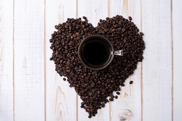 Coffee cup and coffee beans on white wooden table