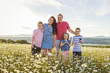 Happy family having fun on daisy field at sunset