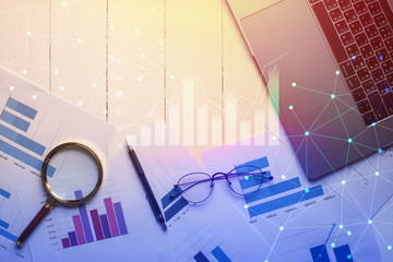 Magnifying glass and documents with analytics data lying on table,selective focus