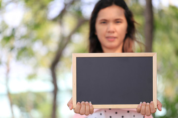 Asian women are pregnant for about twelve weeks to holding a blank blackboard.