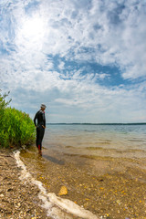 Woman in a wetsuit standing at the Cospudener Lake, open water swimming