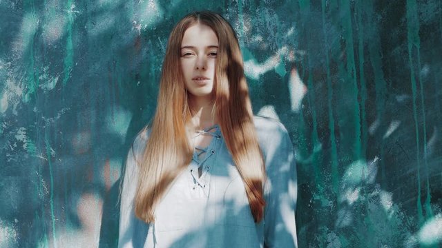 young beautiful woman with shadows on face with long red hair and blue shirt