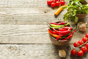 Chili pepper is spicy in a wooden bowl. Tomato parsley garlic on wooden rustic background