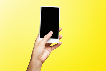 Fototapeta na wymiar Mockup of female hand holding frameless cell phone with black screen isolated at yellow background.