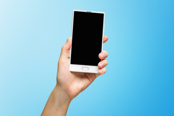 Mockup of female hand holding frameless cell phone with black screen isolated at blue background.