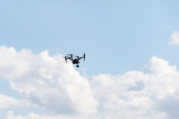 Fototapeta na wymiar Black Drone camera flying in clouds blue heaven sun
