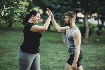 Good job. Plus size woman giving high five to her personal trainer. Fitness instructor, sport, training, weight loss, teamwork and healthy lifestyle concept.