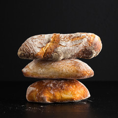 a pile of fresh Italian bread on black background