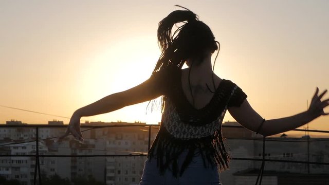 Dancing Female. silhouette happy mixed race woman dancing performance with long dreadlocks in shorts on sunset background