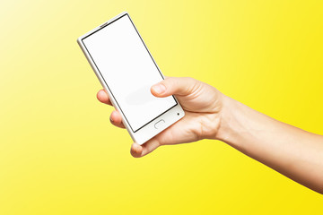 Fototapeta na wymiar Mockup of female hand holding frameless cell phone with blank screen isolated at yellow background.
