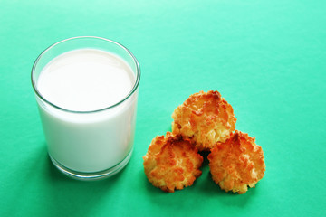 Glass of milk and three cookies on a turquoise background, top view.