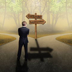 Geschäftsmann steht an Weggabelung von Freihandel und Protektionismus