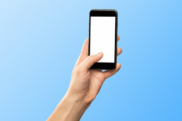 Male hand holding black cellphone isolated at blue background.