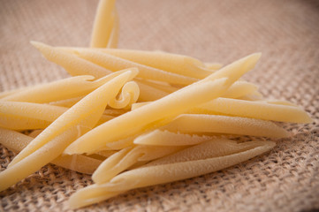 closeup of penne pasta on hessian background