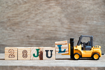 Toy forklift hold block l to complete word 28 jul on wood background (Concept for calendar date in month July)