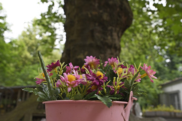 tischschmuck aus kunstblumen im blechkübel in einem gartenlokal