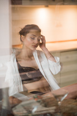 beautiful young girl in lingerie having breakfast with croissant in the kitchen