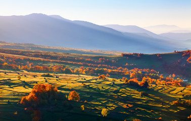 Wonderful scenery with cities with fields and haystacks. Fruit trees with colored leaves. High mountains. Fantastic mountain landscape for postcards.