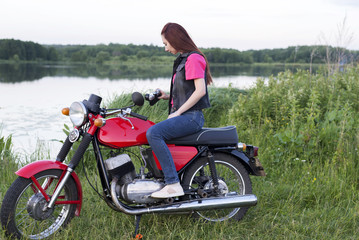 Naklejka na ściany i meble Girl sitting on a vintage motorcycle with a camera