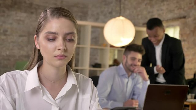 Young beautiful businesswoman is listening how her men colleagues on background gossip about herm, sexism concept, bulling concept