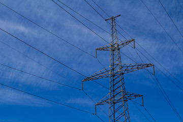 Electric high voltage tower with electric line against clouds blue sky