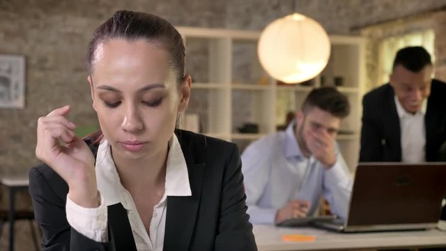 Young beautiful businesswoman is upset about her men colleagues on background gossip about herm, sexism concept, bulling concept