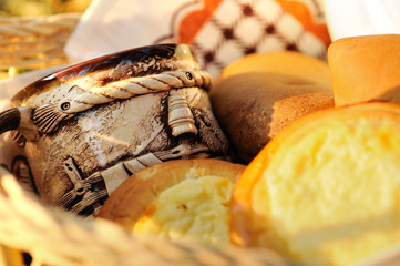 Beautifully lit wicker basket for a picnic with pies, cheesecakes, a beautiful ceramic mug and a bottle of milk.  Moscow region, Russia.
