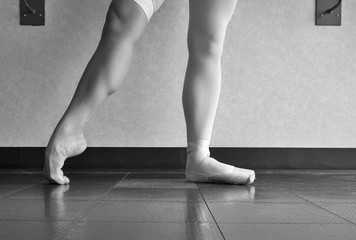 The hardworking disciplined ballerina ballet dancer warming up in her pointe shoes and bare feet, displaying the behind the scenes of a dancer 