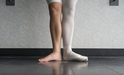 Two sides to a ballerina, one leg wearing her ballet slipper pointe shoe on one foot, and one leg bare © Katherine BYC