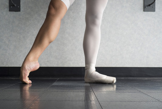 The hardworking disciplined ballerina ballet dancer warming up in her pointe shoes and bare feet, displaying the behind the scenes of a dancer 