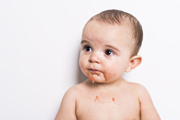 Happy infant baby boy doing a mess eating puree