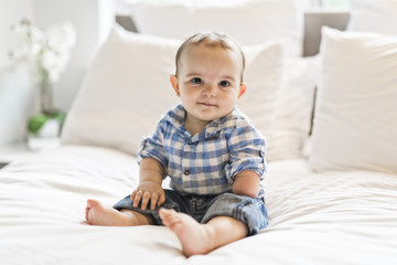 Adorable baby boy in white bedroom in morning