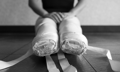 Black and white version of Ballet pointe shoes on a young female ballerina untied in ballet class 