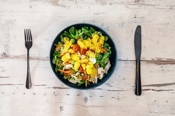 Salad with fusilli pasta accompanied tomatoes, mozzarella, smoked ham and italian cheese