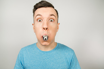 Young guy with bulb in a mouth dressed in a blue t-shirt on a light background.