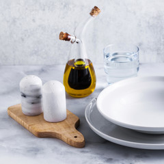 Empty set of plates for soup on a table with spices and olive oil in a decanter.