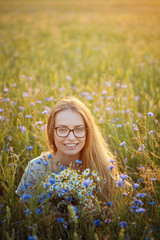 girl with a bouquet of daisies and cornflowers in the field.