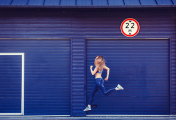 Fototapeta na wymiar Side view of sporty young woman running on sidewalk. oncept with copy space.