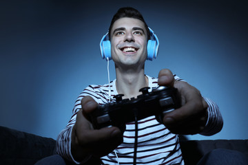 Young man playing video game at home in the evening