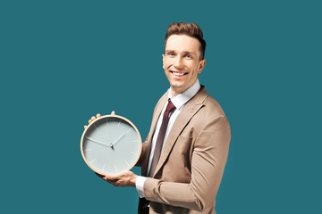 Successful businessman with clock on color background. Time management concept
