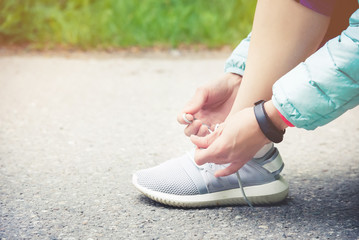 Naklejka premium Girl runner tying laces for jogging her shoes on road in a park. Running shoes, Shoelaces. Exercise concept. Sport lifestyle. Vintage style