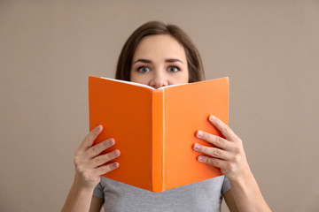 Young woman with book on color background