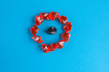 One black plastic gem surrounded by orange on a blue background