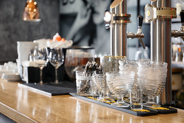 Draft beer taps with glassware on counter in modern bar