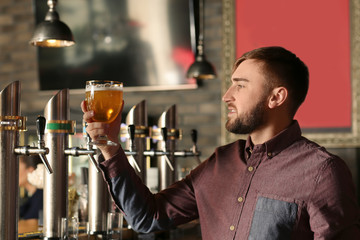 Bartender with glass of beer in bar