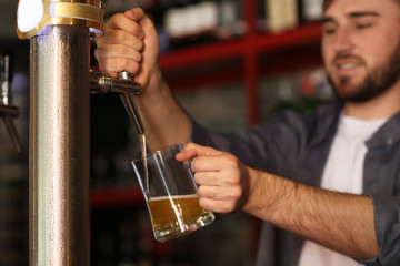 Bartender pouring beer into glass in bar